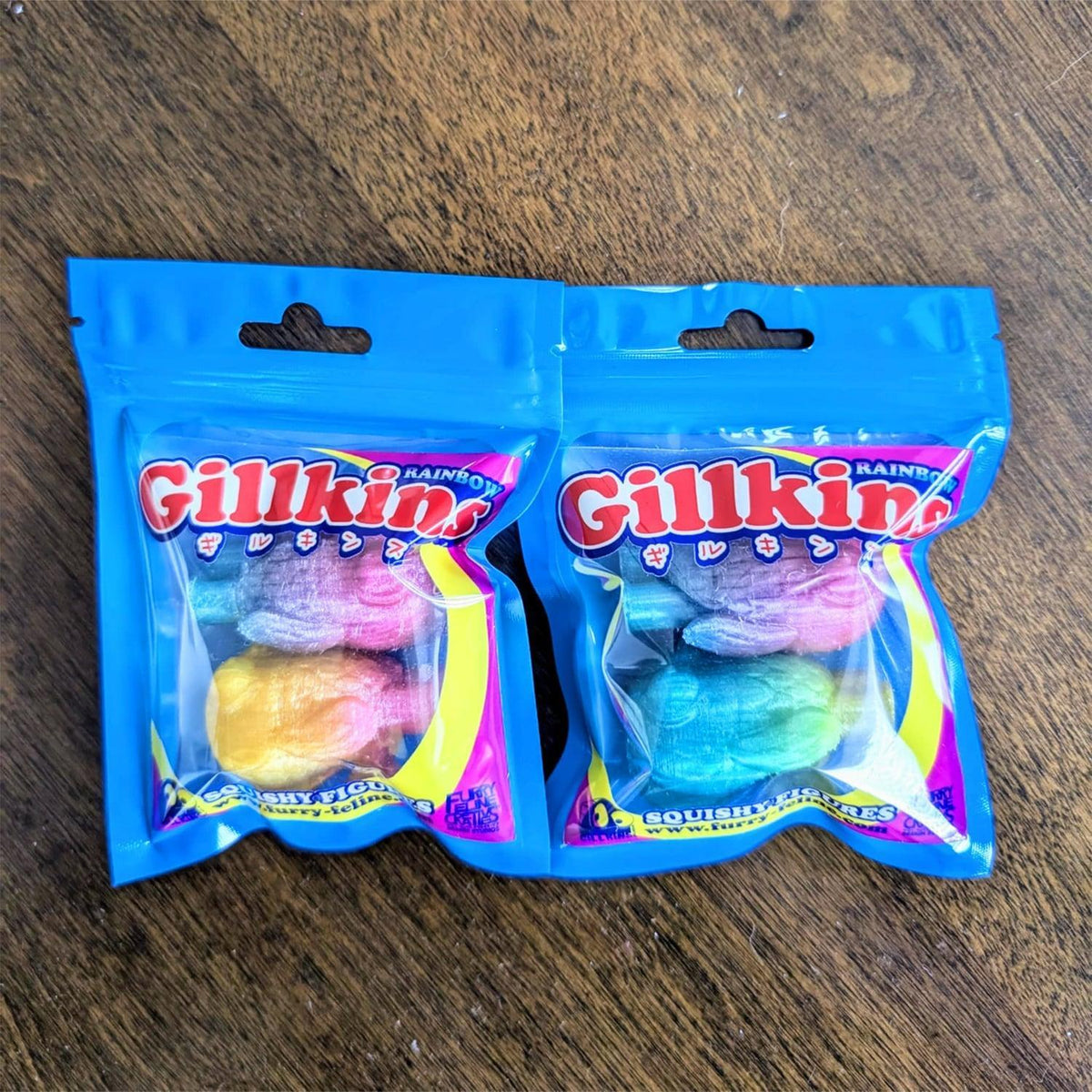Two packages of Gillkin Rainbows on a wooden surface